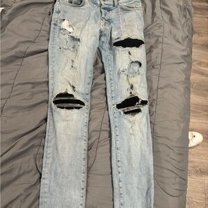 AMIRI Light Blue Ripped Skinny Jeans with Black Patch Detail